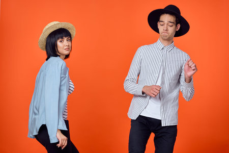 man and woman in hats posing fashion orange background