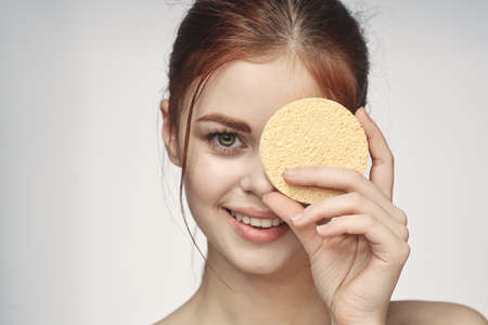woman with a sponge in her hands bare shoulders skin care closeupの写真素材
