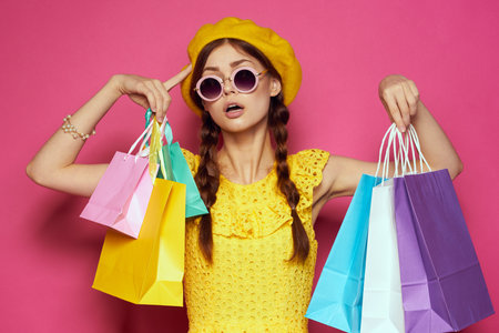 cheerful woman wearing sunglasses posing shopping fashion pink background