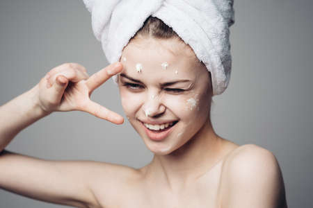 woman with bare shoulders towel on head face cream skin careの写真素材
