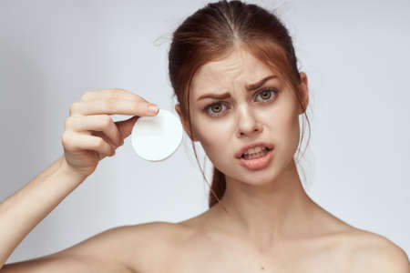 woman with bare shoulders cotton pad clean skin light backgroundの写真素材