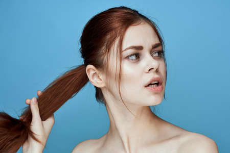 woman with bared shoulders pigtail emotions posing blue backgroundの写真素材