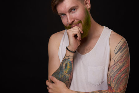 bearded man with tattoos on his arms gesturing with his hands dark backgroundの写真素材