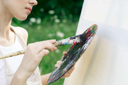 woman artist in white dress paint palette drawing close-upの写真素材