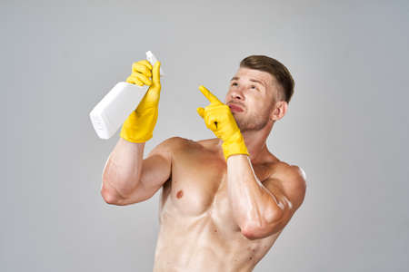 pumped up man posing with detergent in rubber glovesの写真素材