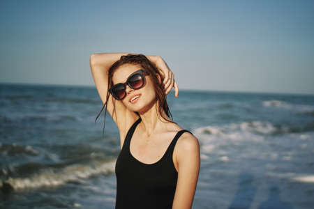 cheerful woman in black swimsuit sunglasses ocean travelの写真素材