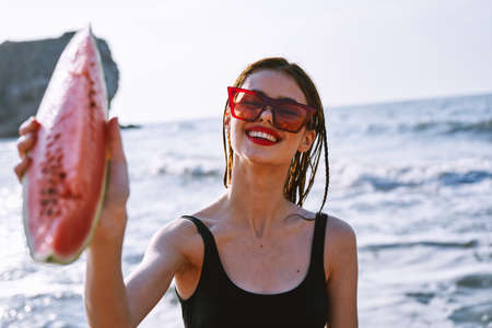 cheerful pretty woman in black swimsuit watermelon fashion travelの写真素材