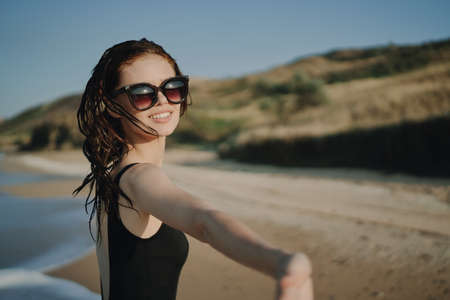cheerful woman in a black swimsuit walking along the beach tropics summerの写真素材