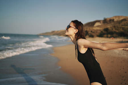 woman walks along the sandy shore in a black swimsuit sun tropicsの写真素材
