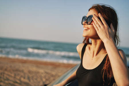 woman on the beach is with a car wearing sunglasses travelの写真素材