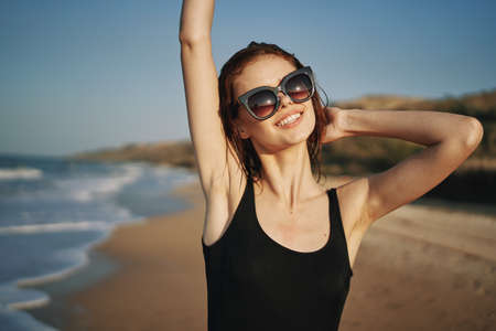 pretty woman in black swimsuit posing sun walking on the beachの写真素材
