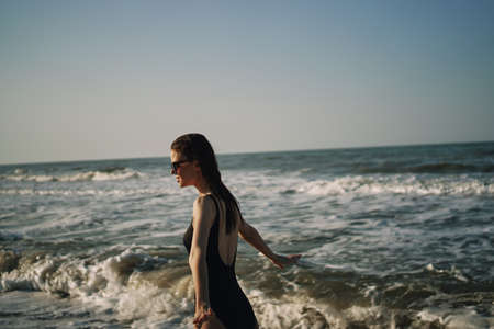 woman in black swimsuit walking on the beach ocean summerの写真素材