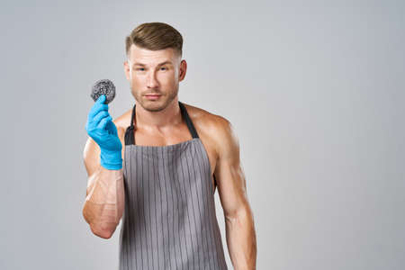 a man in an apron with rubber gloves and an iron sponge serviceの写真素材