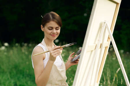 cheerful woman artist painting a picture outdoors creative artの写真素材