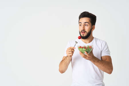 a man in a white t-shirt in a plate with salad a snack healthy foodの写真素材