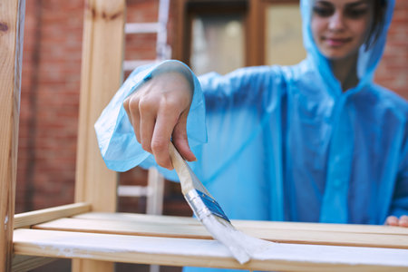 cheerful woman house painter in protective suit repairing home
