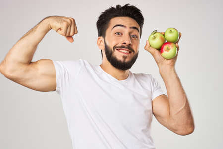 Cheerful man with apples in his hands in a white t-shirt fruitsの写真素材