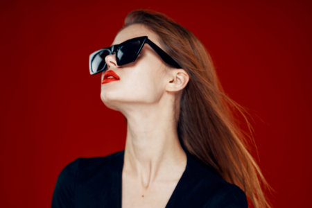 cheerful fashionable woman wearing sunglasses red lips posing red background