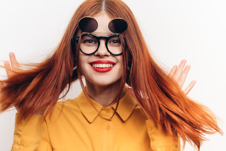 red-haired woman wearing sunglasses posing fashion light background