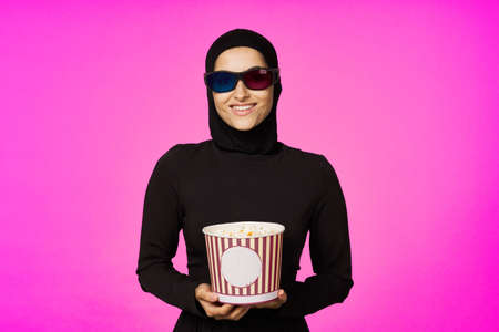 arab woman in 3D glasses popcorn entertainment movies purple backgroundの写真素材