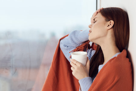 woman with hot near window in plaid rest at home