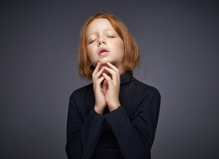 red-haired girl with freckles on her face in a black sweater posingの写真素材