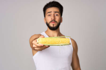 Cheerful man eating corn diet isolated backgroundの写真素材