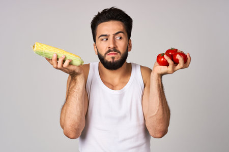 a man in a white t-shirt with vegetables in hands isolated background