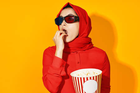 arab woman 3d glasses technology watching movie popcorn yellow backgroundの写真素材