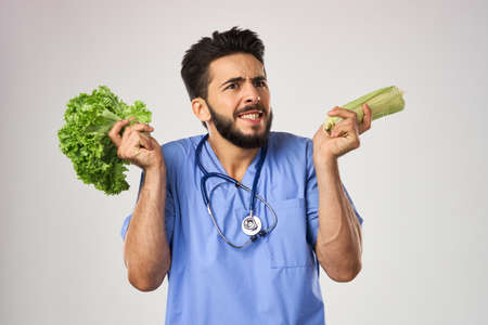 Cheerful dietitian doctor with vegetables in hands stethoscope treatmentの写真素材