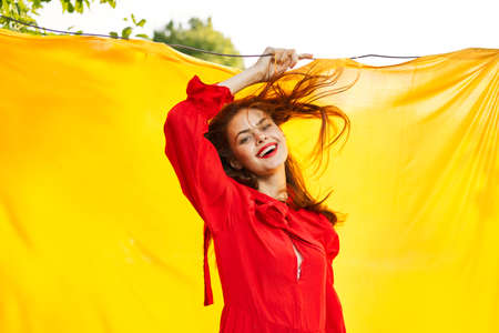 cheerful woman in red dress posing in nature yellow clothの写真素材