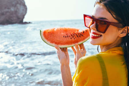 cheerful woman near the ocean with watermelon posingの写真素材