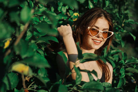 cheerful fashionable woman in sunglasses and green leaves russian summerの写真素材
