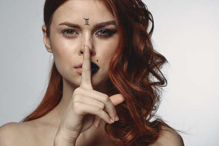 pretty woman with zodiac sign on her face red hair close-upの写真素材