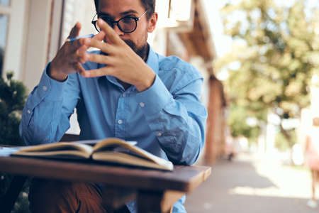 A man sits at a table in a summer cafe documents telephone communicationの写真素材