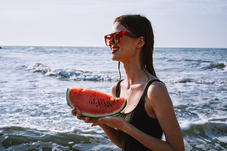 woman in black swimsuit with watermelon by the ocean