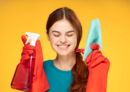 woman in rubber gloves detergent cleaning housework yellow background