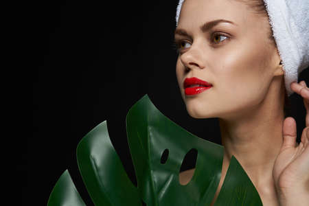 attractive woman palm leaf bare shoulders clear skin dark backgroundの写真素材