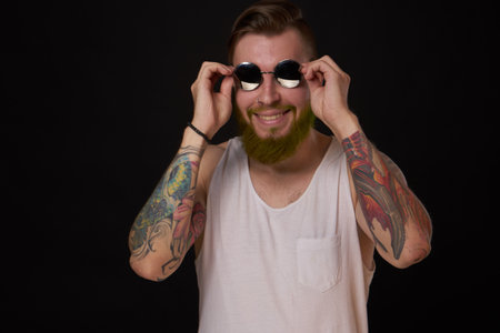 handsome man with tattoos on his arms fashion sunglasses dark backgroundの写真素材