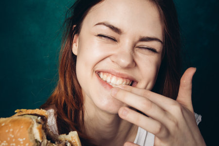 woman eating hamburger fast food snack close-upの写真素材