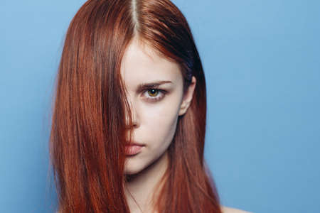 attractive woman with bare shoulders red hair close-up blue backgroundの写真素材