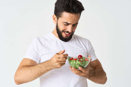 a man in a white t-shirt in a plate with salad a snack healthy foodの写真素材