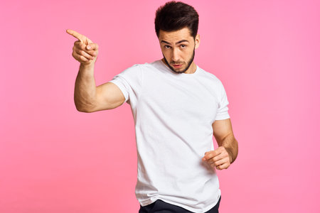 a handsome man in a white t-shirt gesturing with his hands on a pink background