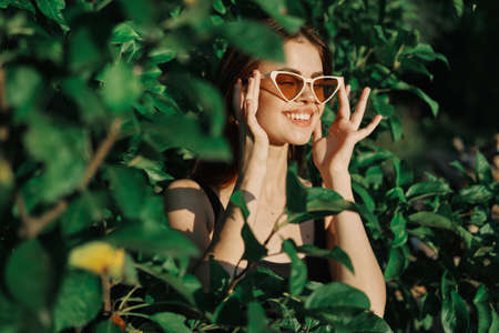 smiling woman wearing sunglasses green leaves nature fashionの写真素材