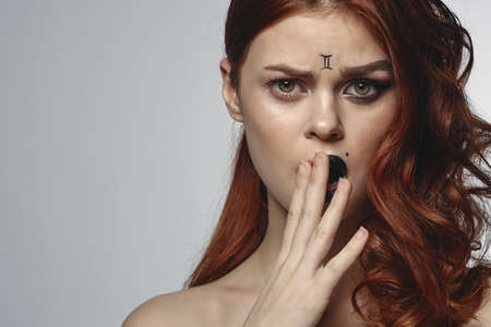 pretty woman with zodiac sign on her face red hair close-upの写真素材