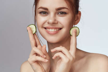 cheerful woman with cucumbers bare shoulders skin care cosmetologyの写真素材