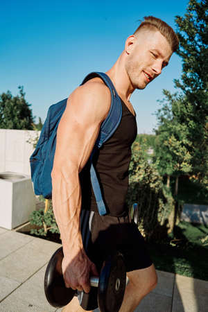 athletic man with dumbbells in his hands in the park training lifestyleの写真素材