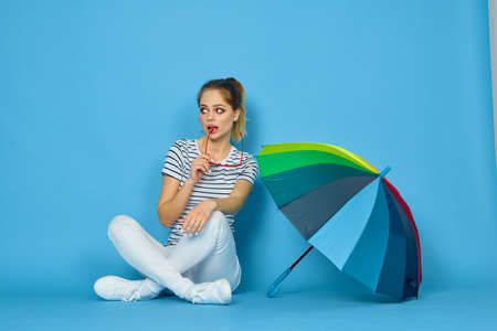 pretty woman fashion posing colorful umbrella blue backgroundの写真素材