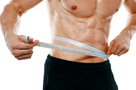 athletic man with pumped up muscular body measures with tape