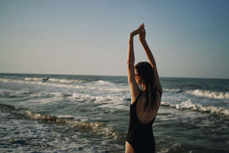 woman in black swimsuit walking on the beach ocean summerの写真素材